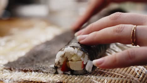 Mano-De-Niña-Sosteniendo-Rollo-De-Sushi-Verde,-Preparación-Casera