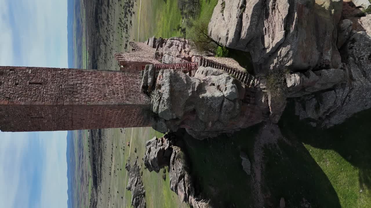vista aérea de un avión no tripulado que se acerca, en modo vertical, a la torre principal de un castillo medieval construido en la cima de una colina rocosa