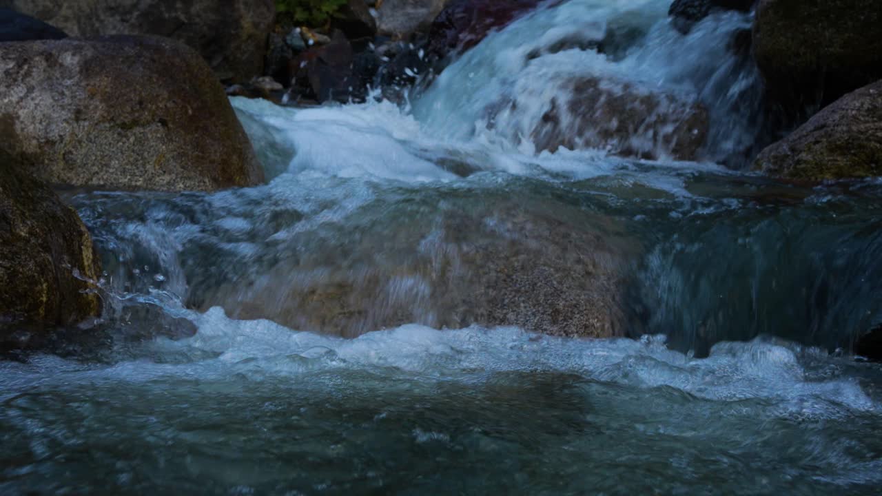 Clear stream running through stone boulders Abundant river flowing on the stone bottom in slow motion. Wild mountain river water splashing on a summer day. underwater bubbles. split view. 4K