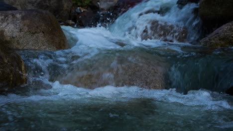 clear stream running through stone boulders abundant river flowing on the stone bottom in slow motion. wild mountain river water splashing on a summer day. underwater bubbles. split view. 4k