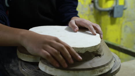 close up over a mexican craftswoman molding a large piece of heart shaped clay figure