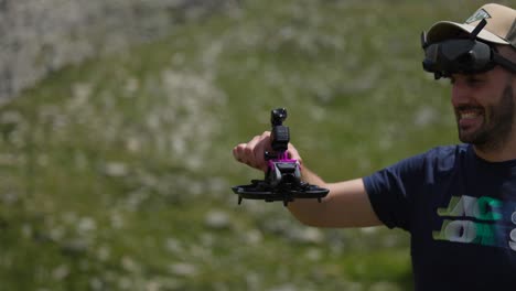 piloto de avión no tripulado feliz sostiene quadcopter con cámara de acción montada en la parte superior con paisaje de montaña en el fondo
