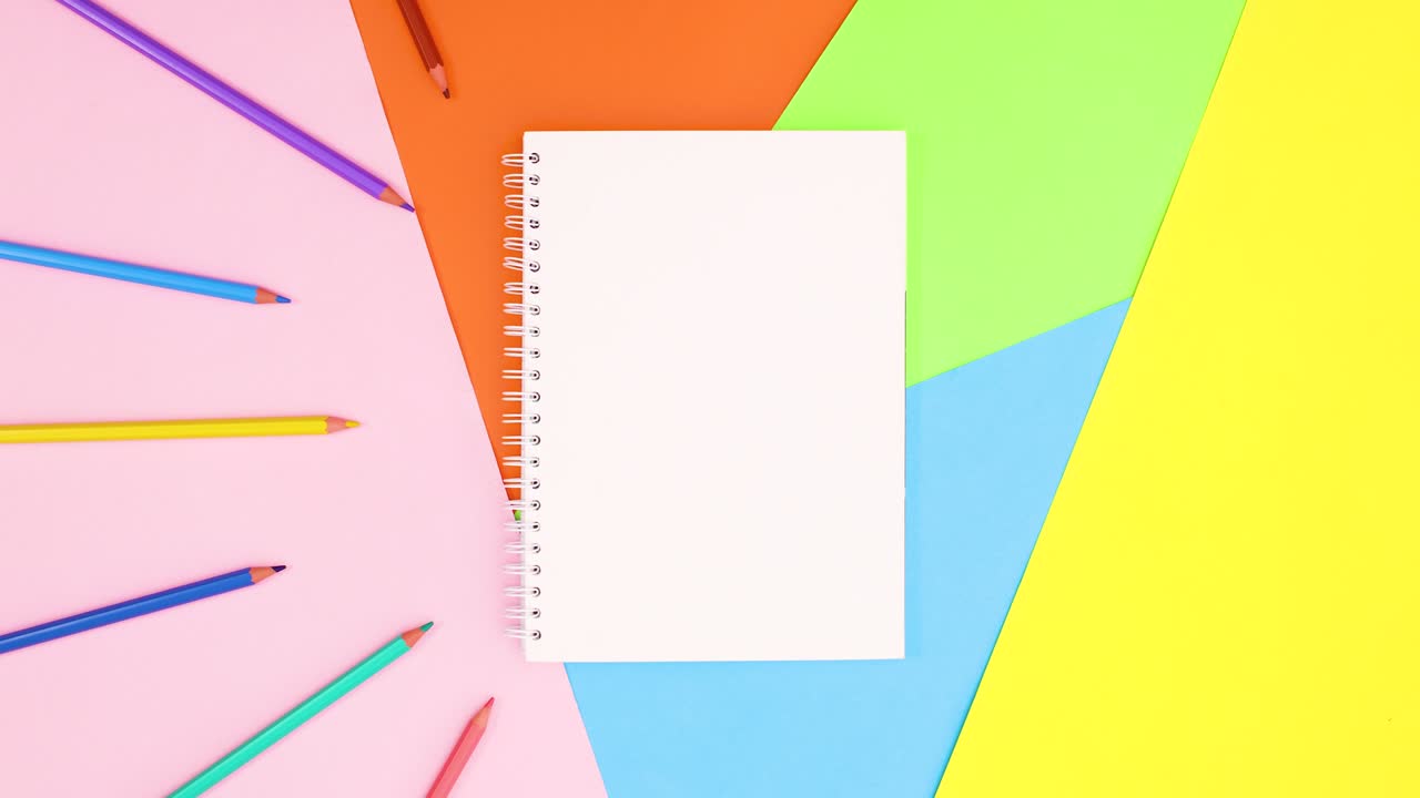 los lápices de colores aparecen y desaparecen en círculo alrededor del cuaderno.