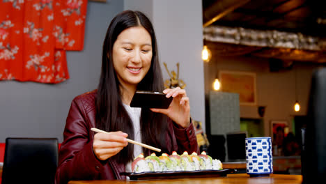 mujer tomando fotos de sushi con teléfono móvil 4k