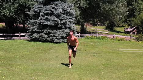 young caucasian fit attractive male sprinter running exercising outdoors with green vegetation background slow motion aerial