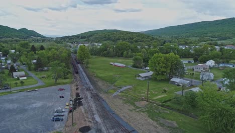 an aerial view of an abandoned narrow gauge coal rail road with rusting hoppers and freight cars and support building starting to be restored