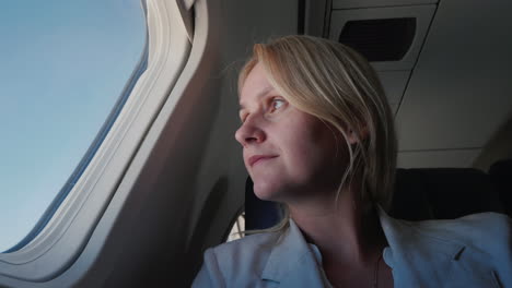 retrato de una pasajera confiada que vuela en un avión mirando por la ventana