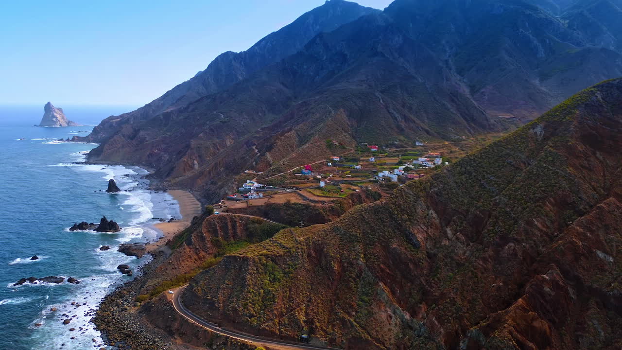 Breath-taking mountains with scarce vegetation at the shore of the Atlantic Ocean. Residential area is located on the rocky coast. Aerial view on Tenerife, the Canary Islands, Spain