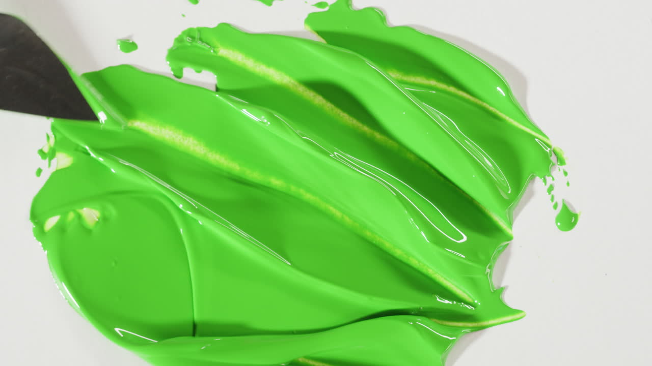 Spatola che Stende Pittura Verde Intensa su Fondo Bianco