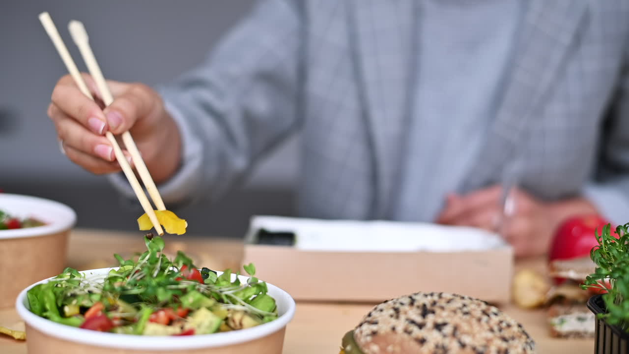 A person is savoring a colorful salad and sushi using chopsticks at a comfortable table. The atmosphere is relaxed, perfect for enjoying healthy dishes