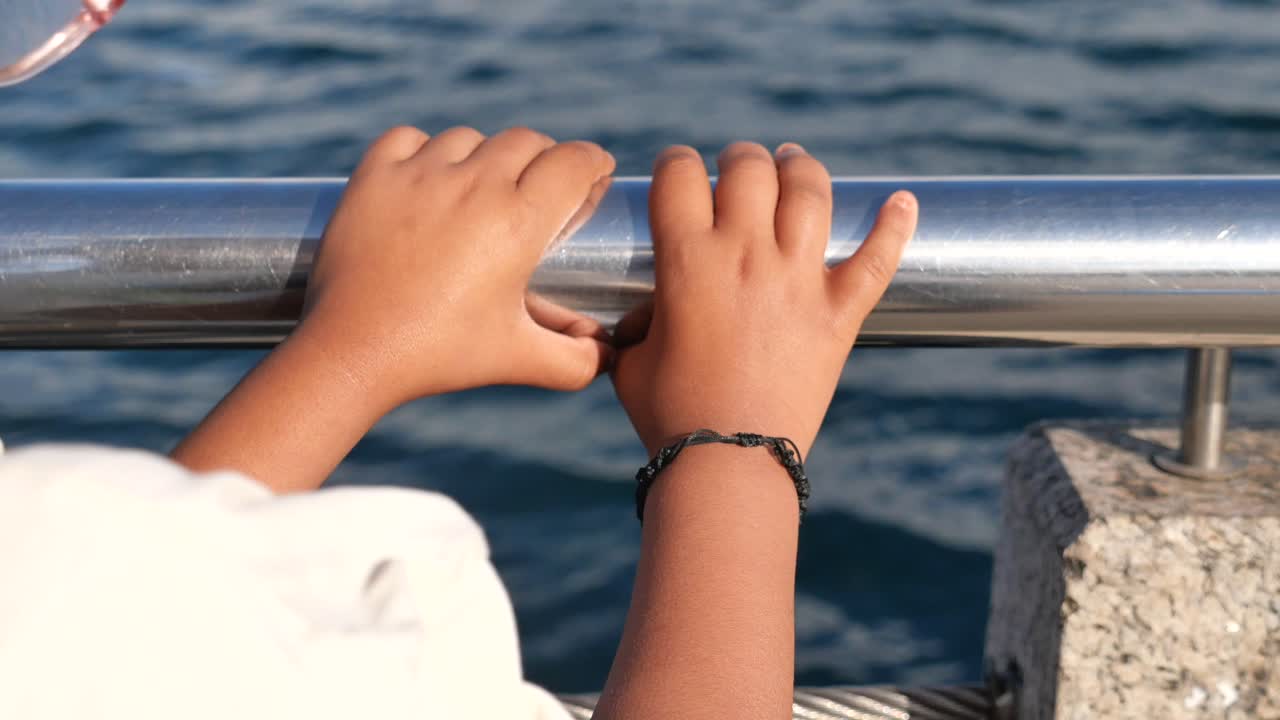 Child's Hands Holding a Railing Over Water