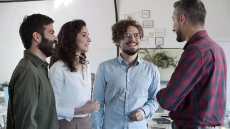 compañeros de trabajo jóvenes sonrientes de pie y hablando en la oficina