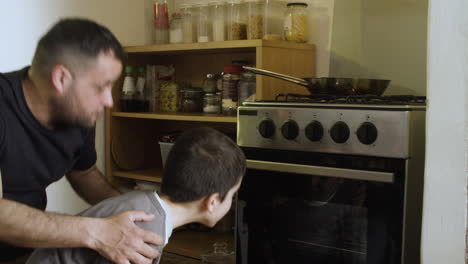 padre soltero con hijo mirando el horno de horneado en la cocina.