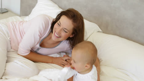 Mother-playing-with-her-baby-daughter-on-the-bed