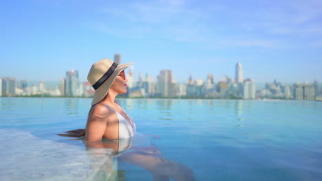 Sensual-Mujer-Asiática-Se-Relaja-En-Una-Lujosa-Piscina-De-Borde-Infinito-Con-Una-Vista-Increíble-Del-Paisaje-Urbano-De-Bangkok-En-El-Fondo