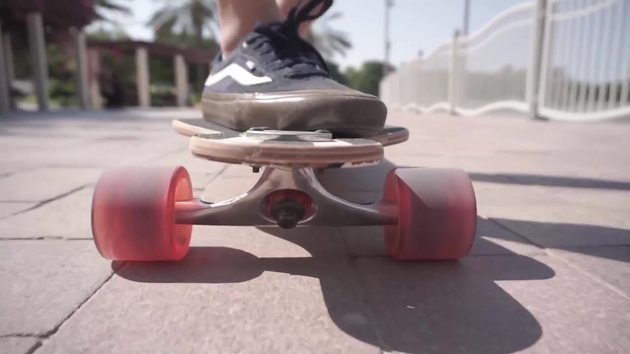 Man in dark blue shoes riding a long board in a park 60 fps