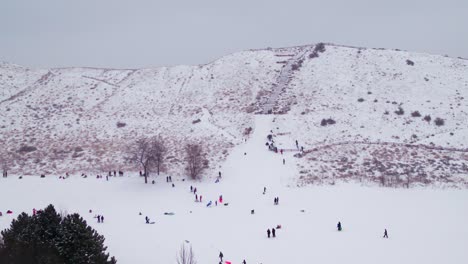 Tiro-De-Drone-De-Niños-Jugando-En-Una-Colina-Nevada-En-Boise,-Idaho