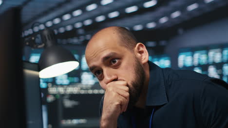 Overworked engineer feeling stressed while coding in data center
