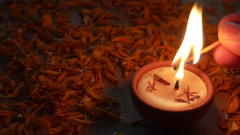 close up of a human lighting a diya or a tradition lamp used for various hindu festive celebrations for the festival of light- diwali and also for others like dussehra or prayers at home or a temple