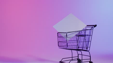 video of shopping trolley and canvas with copy space over neon pink background