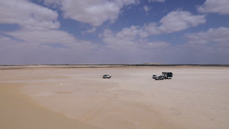 Cars-walking-on-the-sand-under-a-cloudy-sky-in-the-desert---wide-shot