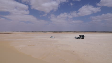 coches caminando por la arena bajo un cielo nublado en el desierto - tiro ancho