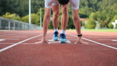 sporty runner goes to starting position on running track