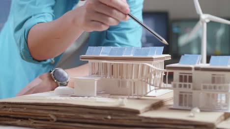 primer plano de un hombre y una mujer ayudándose mutuamente a construir el modelo de una pequeña casa con panel solar