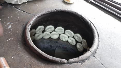Food vendor putting flat dough in clay oven to make grilled Chinese flat bread or &quot;Huping&quot; in traditional way