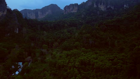 limestone cliffs and lush tropical jungle of railay beach, krabi, thailand, at dusk, creating a dramatic and serene landscape. lovely aerial view flight descending drone