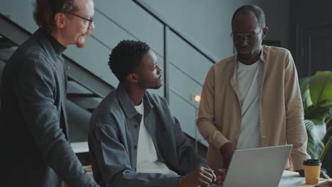 group of male office workers discussing business data on laptop