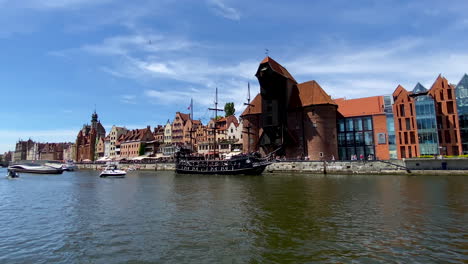 gdansk old town - wooden tourist ship stylized as a pirate boat and modern yachts on the motlawa river near crane in the historical part of gdansk daytime