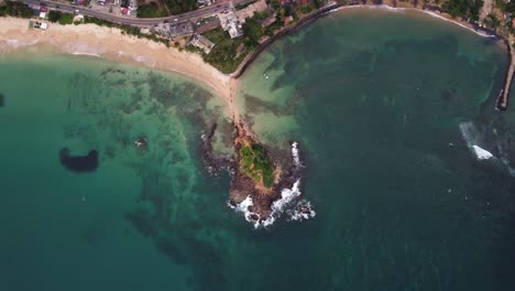 aerial drone panning top view over tropical pigeon island with rocky beaches, clear ocean and coastal roads in asia tourist destination, sri lanka