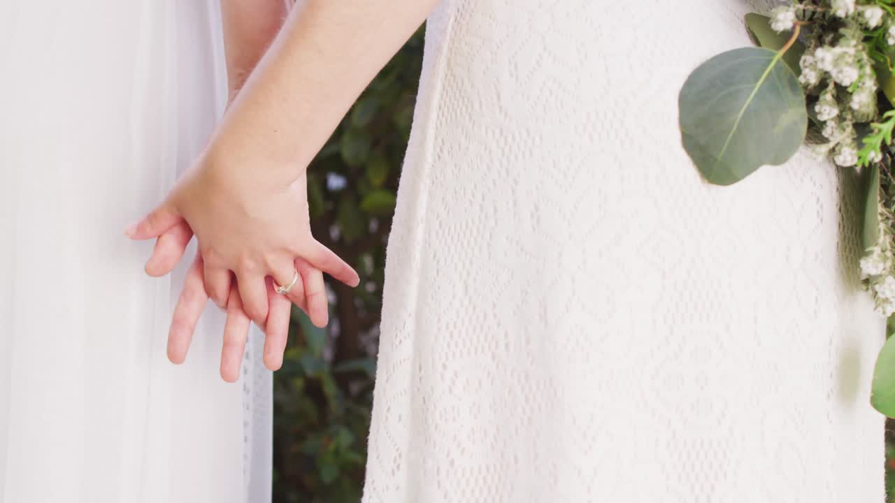 다양한 여성 커플이 손을 잡고 정원에서 꽃을  ⁇ 고 있습니다.