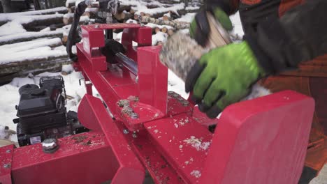 a man using a mechanical wood splitter in winter forest