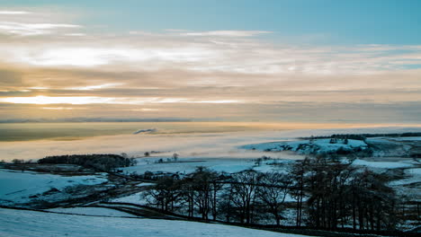 cloud inversion covering the eden valley in cumbria with the lakeland mountains in the background, and the sun breaking through the clouds and lighting up the foreground