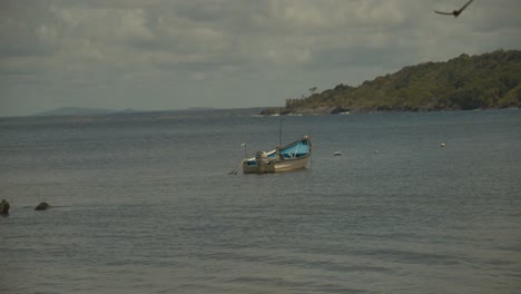 un barco de pesca anclado en el mar con montañas al fondo