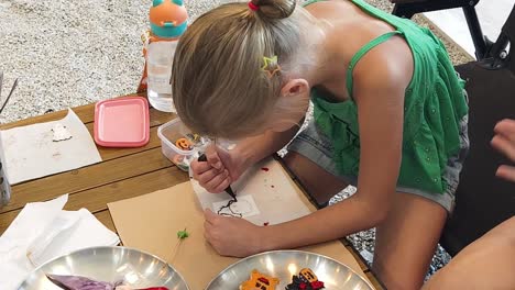 child decorating halloween cookies