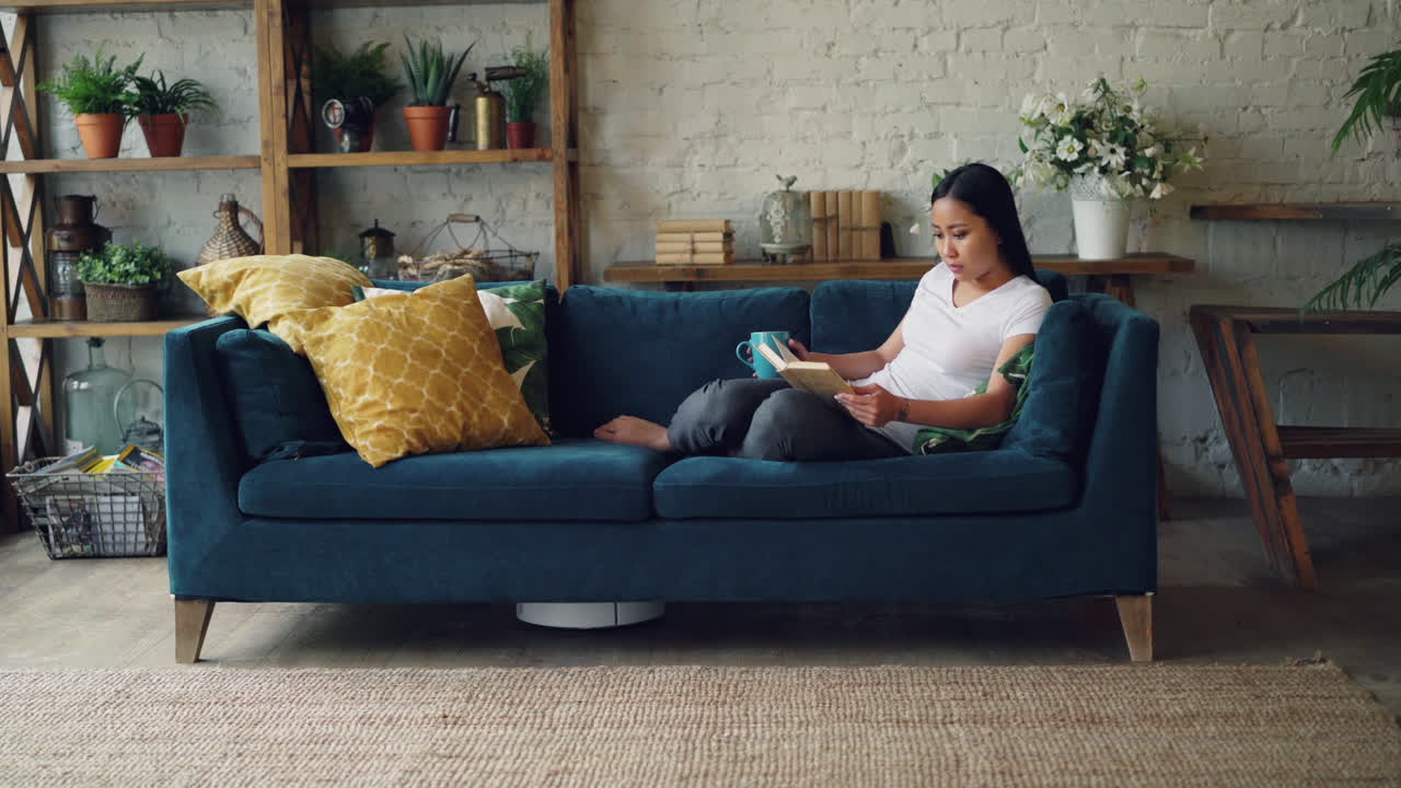 mujer relajándose en un sofá y leyendo un libro