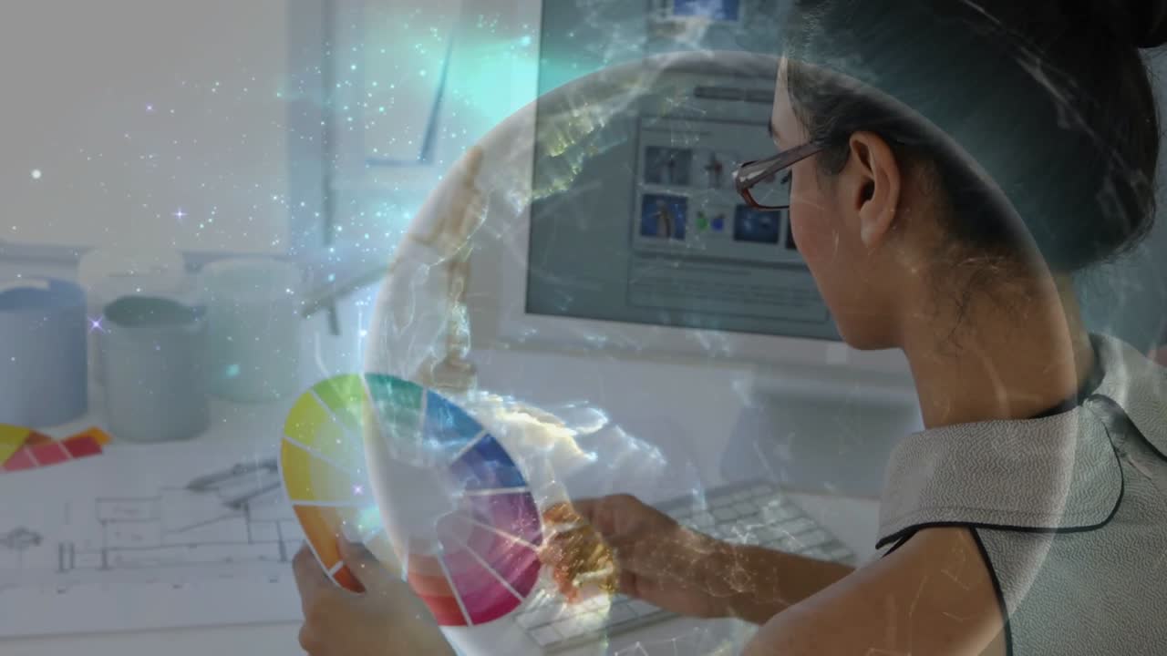 While typing, designer lifting color wheel, rotating, tapping screen, globe brightening for palette