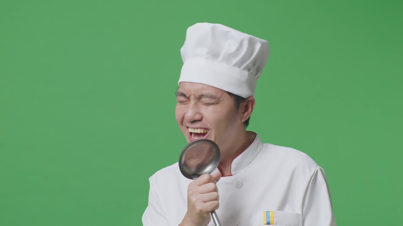 Close Up Of Asian Man Chef Holding Ladle And Singing While Standing In The Green Screen Background Studio