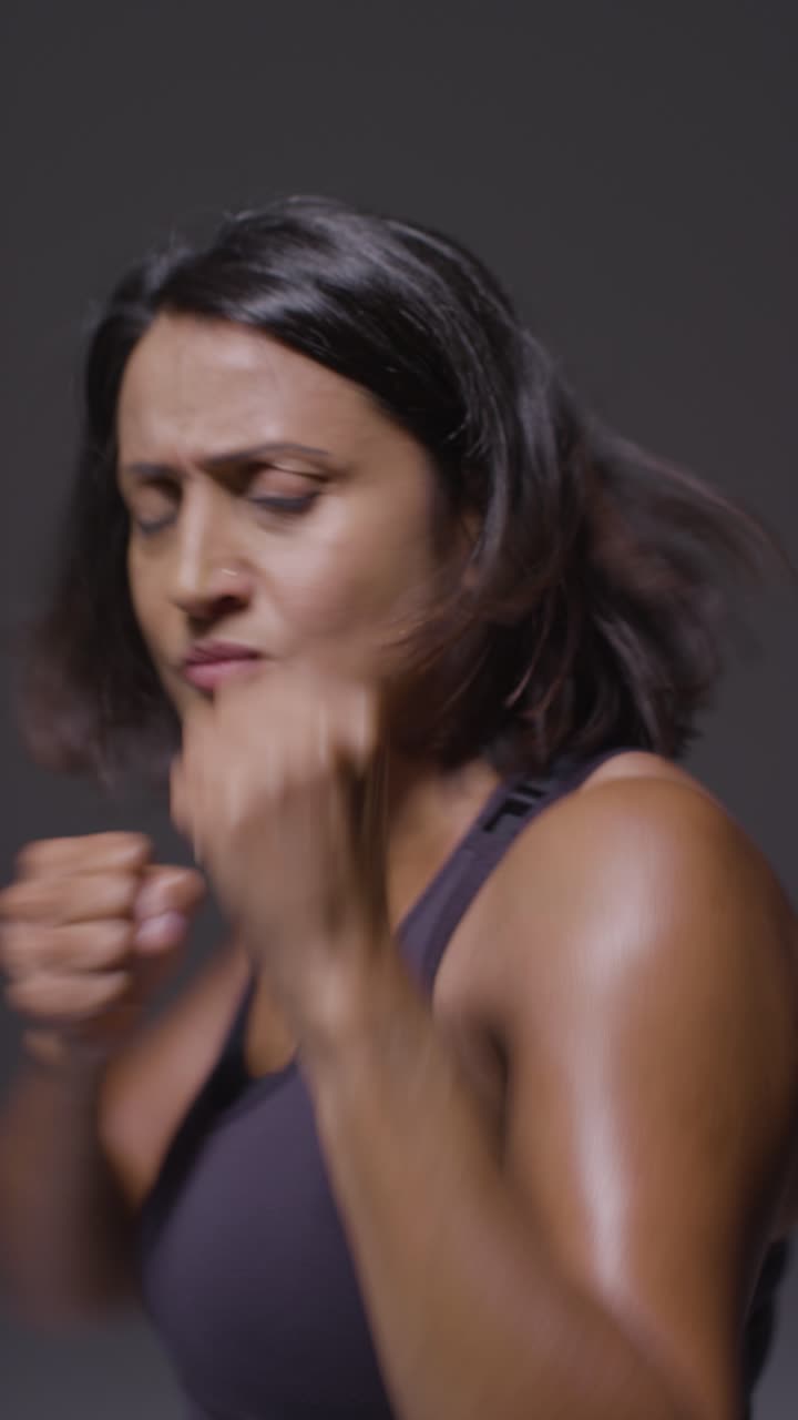 Vertical Video Studio Portrait Of Mature Woman Wearing Gym Fitness Clothing Exercising Sparring At Camera