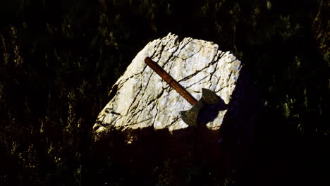 rustic axe resting on a weathered stone in a grassy setting at dusk