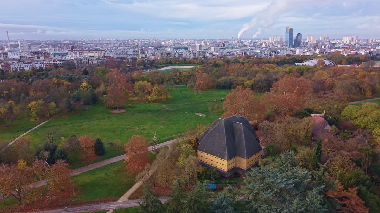 Drone view above Bois de Vincennes showing autumn trees, park paths and Paris skyline
