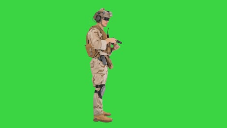 young man in military uniform checking revolver gun on a green screen, chroma key