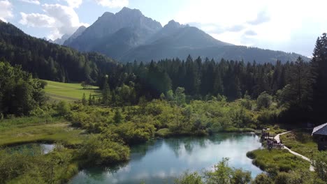 zelenci nature reserve at slovenia - aerial drone view of the blue emerald lake, wooden boardwalks and high mountains