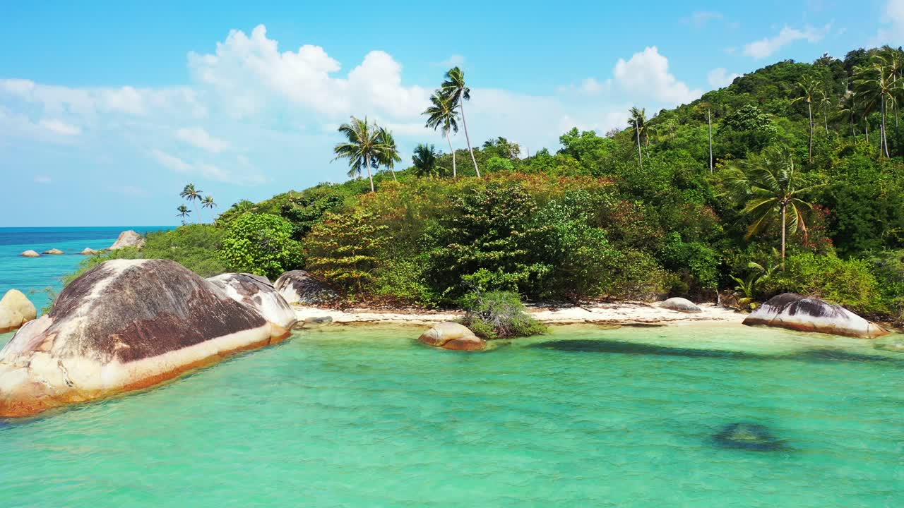Limestone cliffs caved by shallow water of turquoise lagoon on beautiful shore of tropical island with palm trees