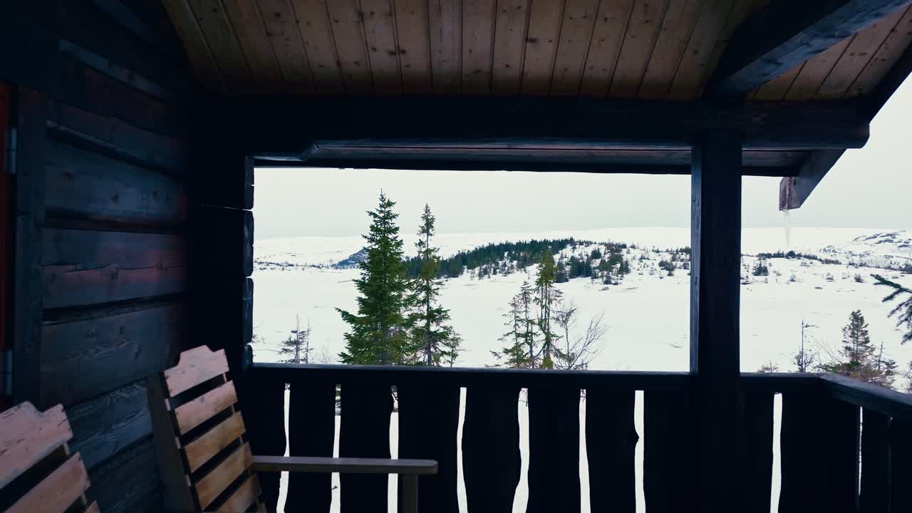 terraza de una cabaña de madera con vistas al paisaje blanco durante el invierno