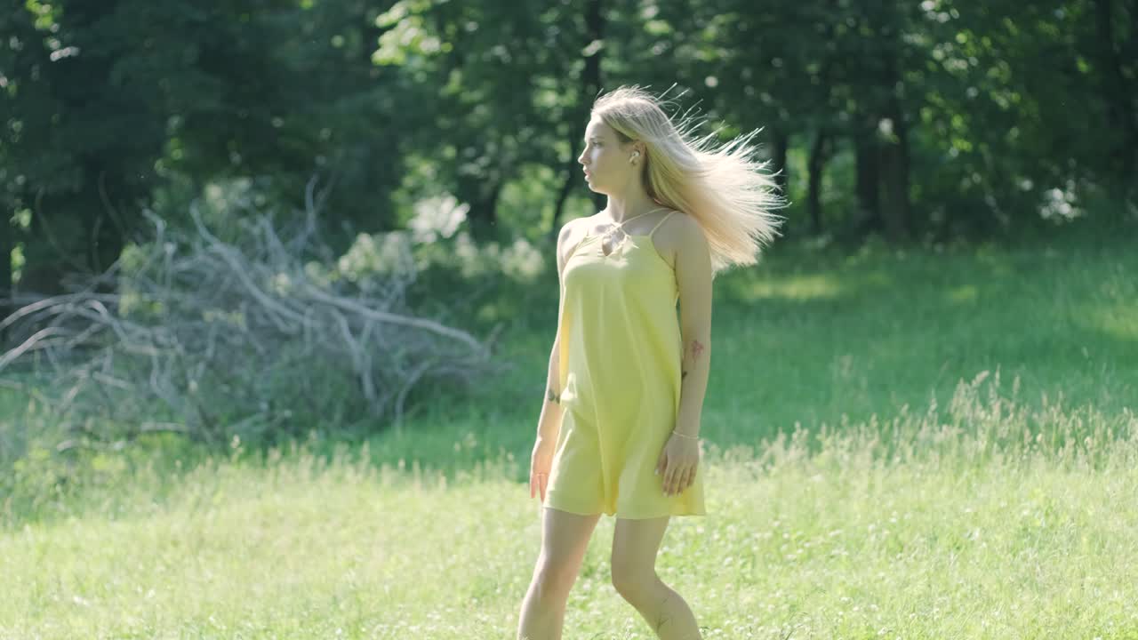아름다운 젊은 소녀가 자유의 춤을 추고 있습니다. 여름 공원에서 뒷면에 나무가 있습니다.