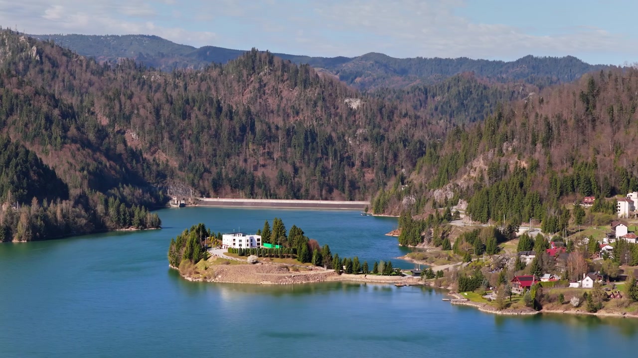 Vista aérea de drone do Lago Colibita com uma pequena península com edifícios, na Romênia.